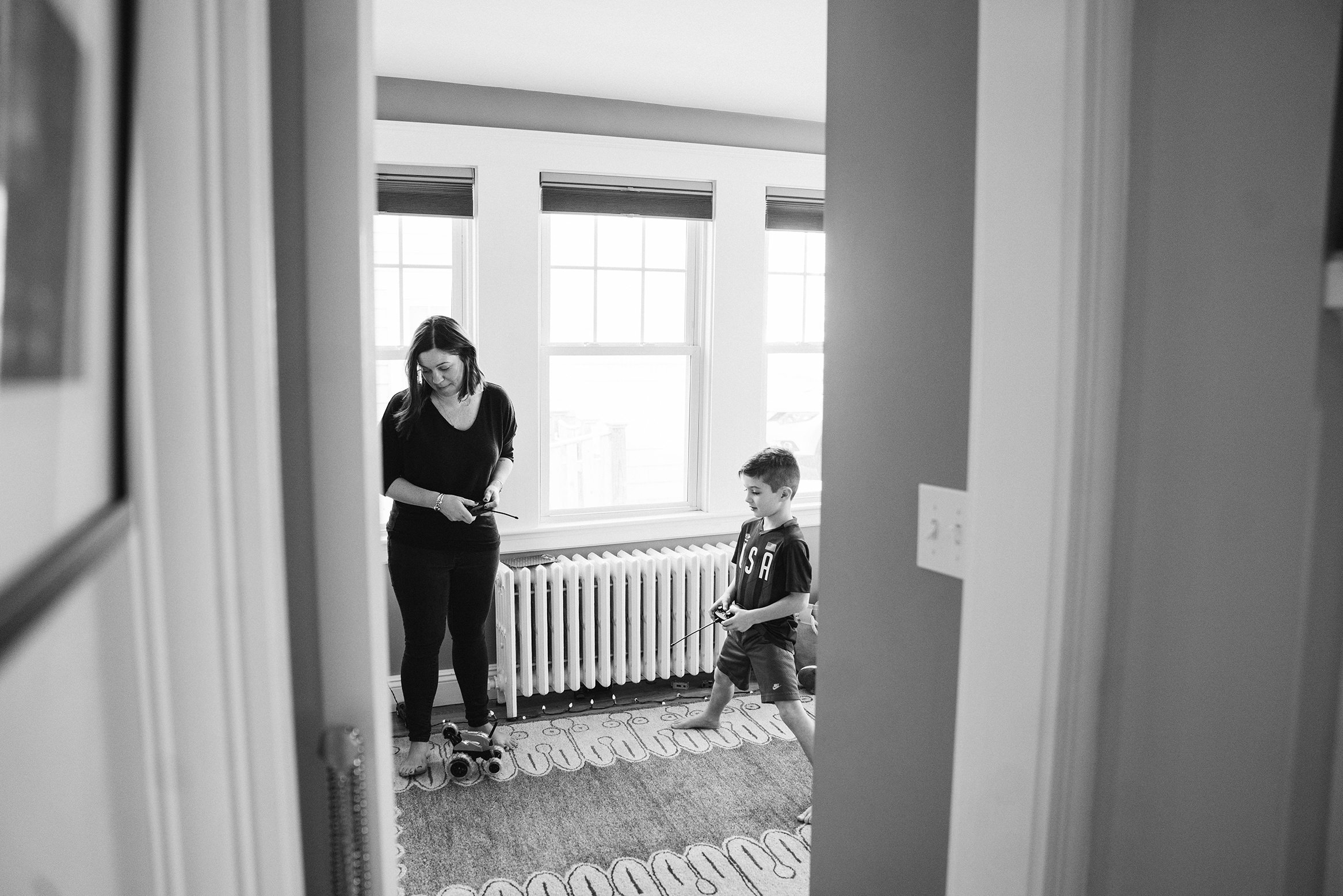 A best of Boston family photograph of a mom and son playing with remote control cars during their in home family session in Boston