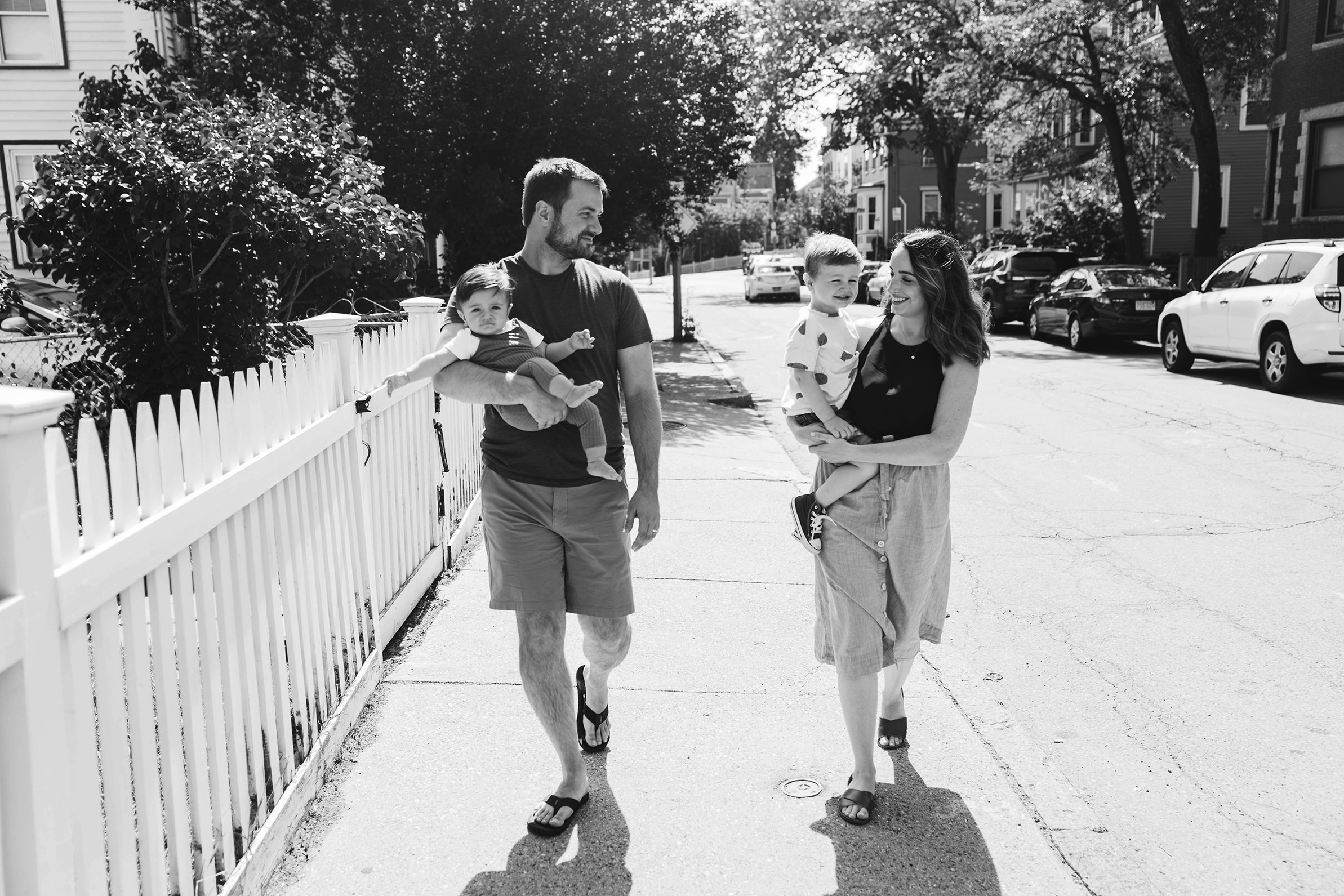 A documentary photograph of a family walking on the sidewalk during an in home family session in Boston