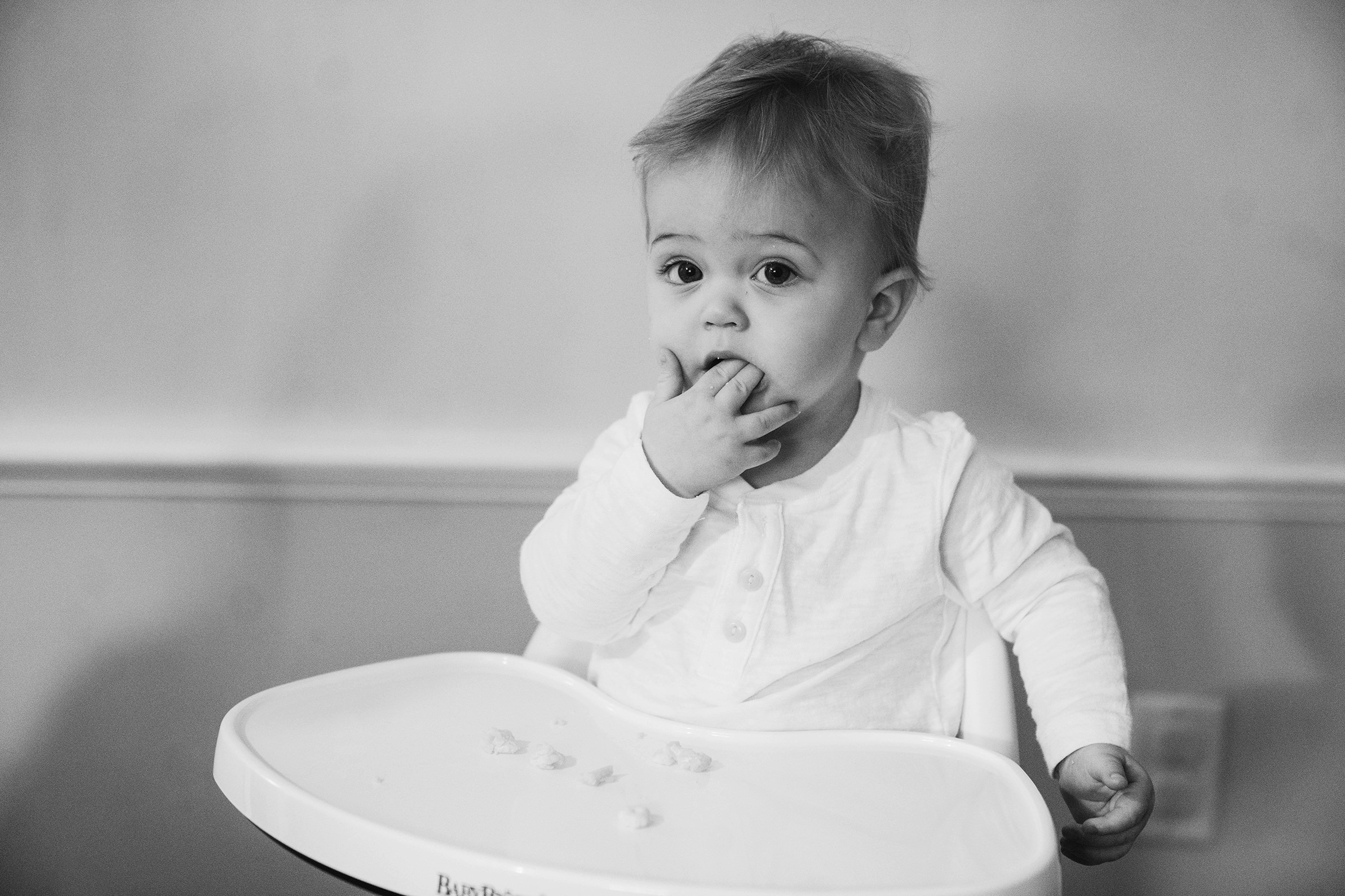 A documentary portrait of a baby having a snack during an in home family session in Boston.