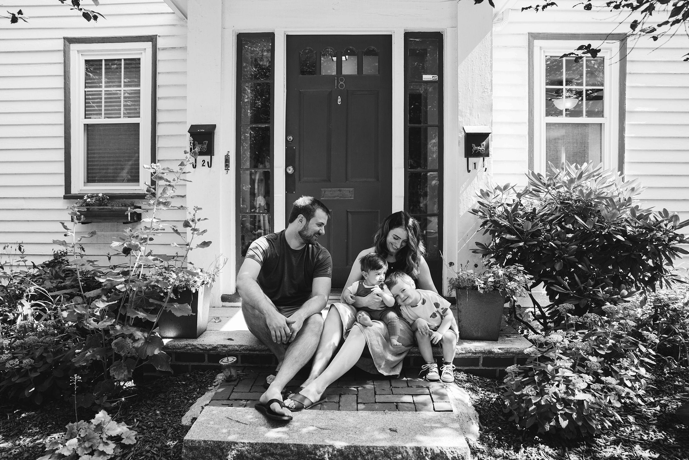 A documentary photograph of family sitting on their porch during an in home family session in Boston