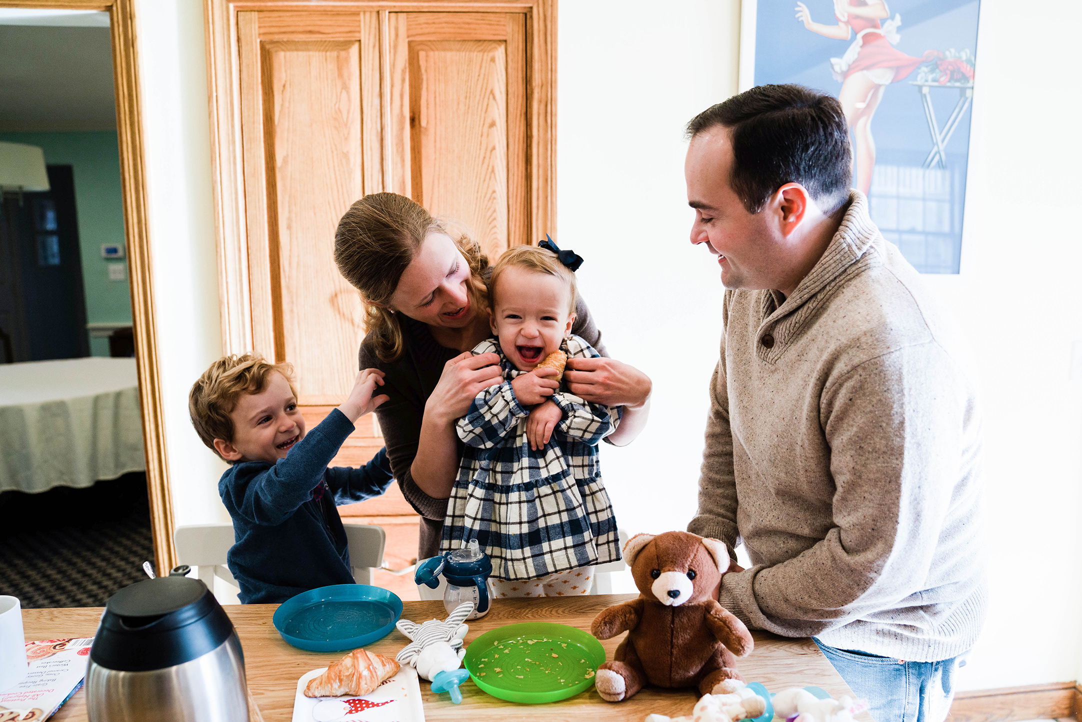 A documentary photograph of a family laughing and tickling each other while eating breakfast during an in home family session in Boston