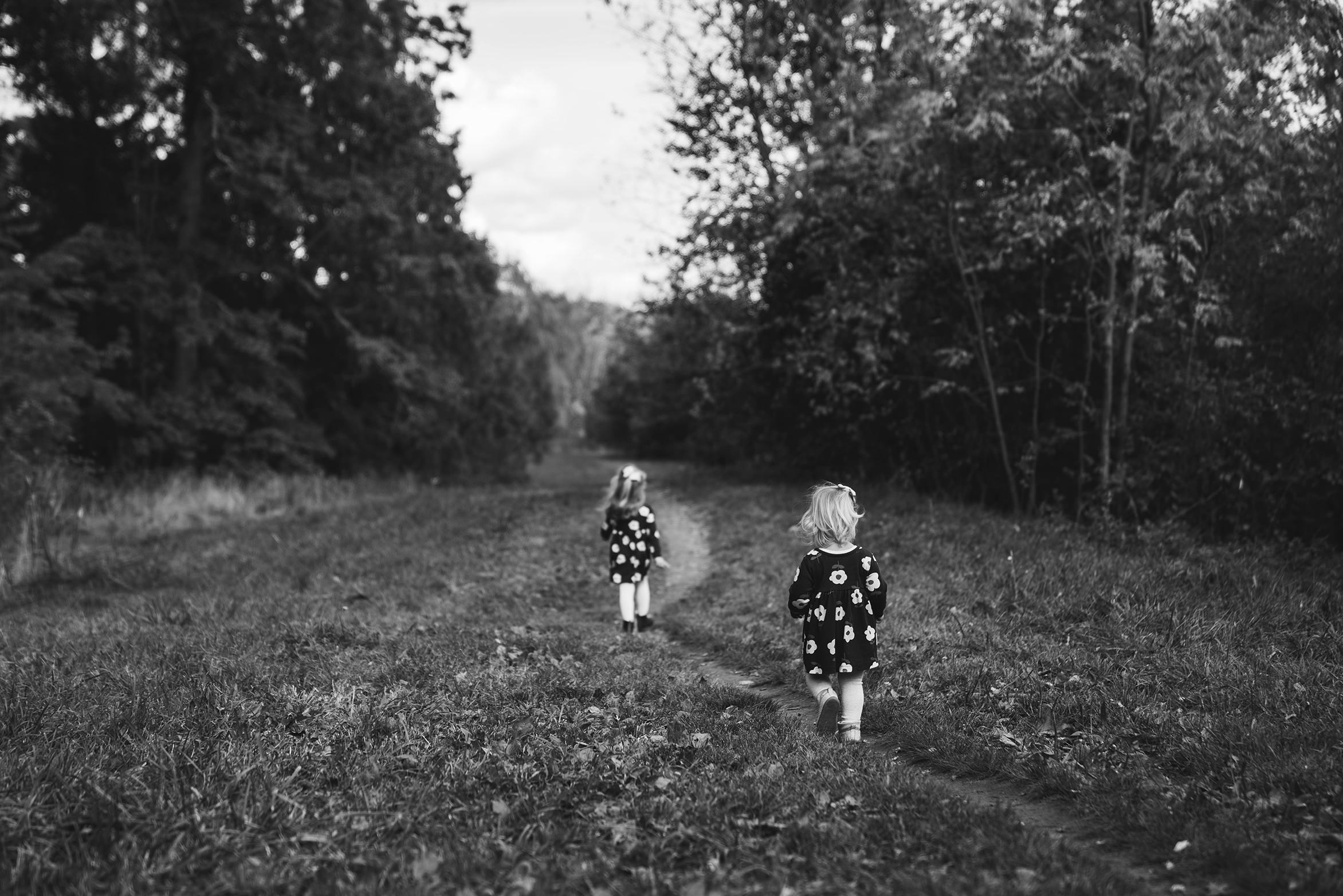A documentary photograph of sisters walking on a trail during a family photo session in Boston
